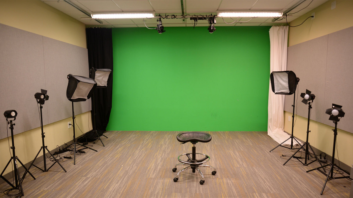DMC Video and Photography Studio DMC video studio has 2 ceiling mounted lights, 7 lights on the floor and a green wall.