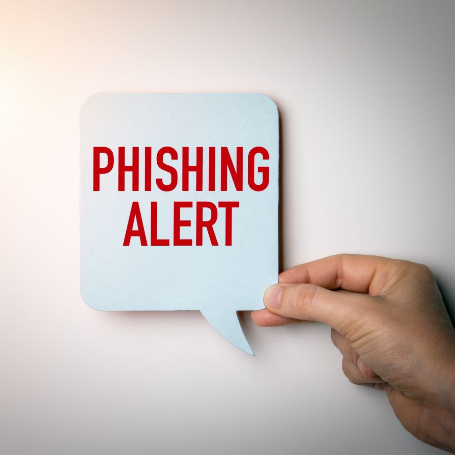 hand holding a paper cutout of a speech bubble with the text phishing alert